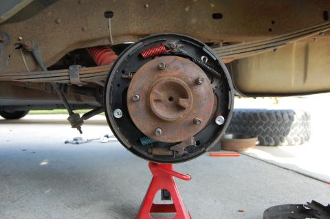 1994 Ford Bronco - Close-up view of a rear drum brake assembly, supported by a red jack stand.