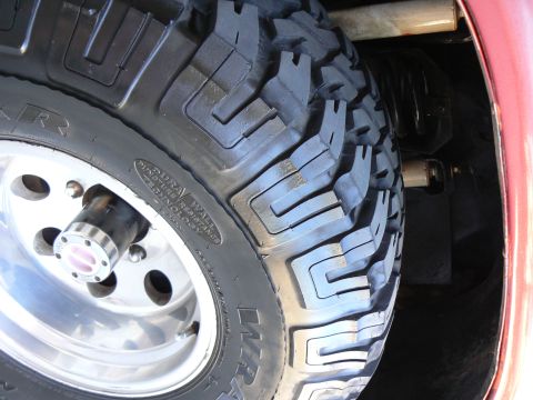 1978 Ford Bronco - A close-up view of a off-road tire and wheel assembly, showing detailed tread pattern and suspension parts.