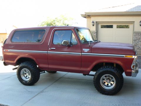 1978 Ford Bronco - Side view of a red 1978 Ford Bronco, identified by its badge, parked on a paved driveway.