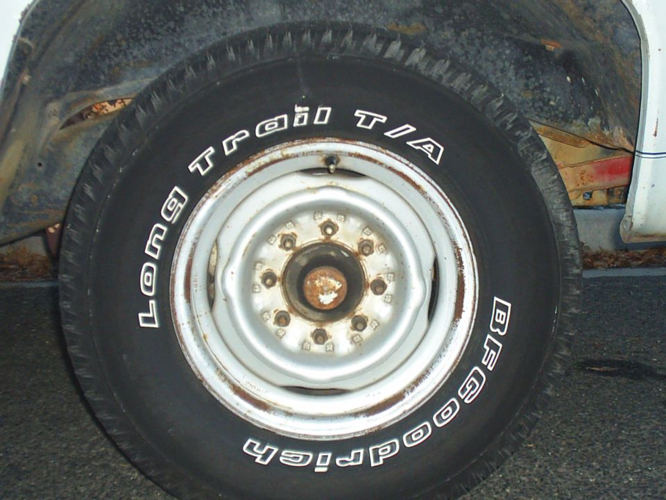 BFGoodrich Long Trail T/A tire on a rusty metal wheel, showing rust on the vehicle body