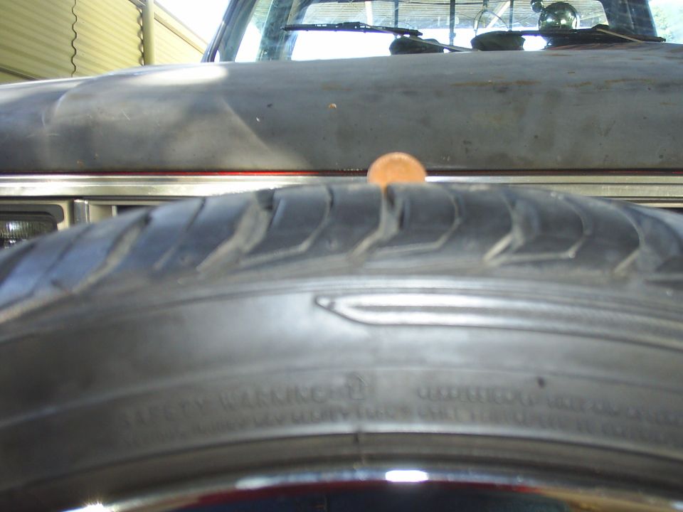 Tire in foreground, penny on hood of a truck