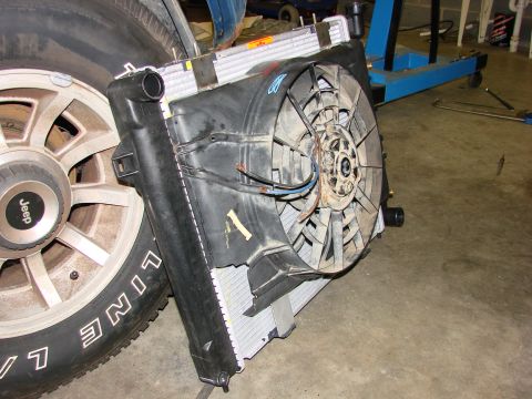 1991 Jeep Comanche - Radiator and fan assembly removed from a vehicle, shown next to a Jeep branded wheel.