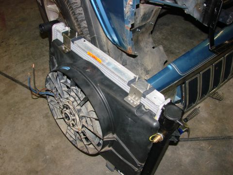 1991 Jeep Comanche - Close-up of a vehicle's radiator and fan assembly, with parts of the blue body and tire visible.