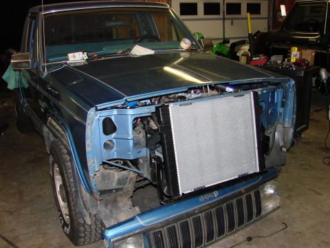 1991 Jeep Comanche - Front end of a blue 1991 Jeep Comanche is disassembled, revealing the radiator and engine components.