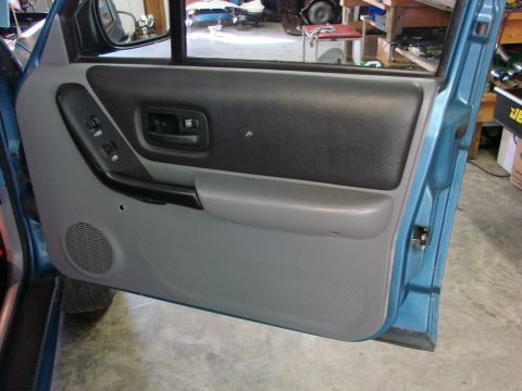 1991 Jeep Comanche - Close-up view of the driver's side interior door panel, revealing the power window controls and speaker.