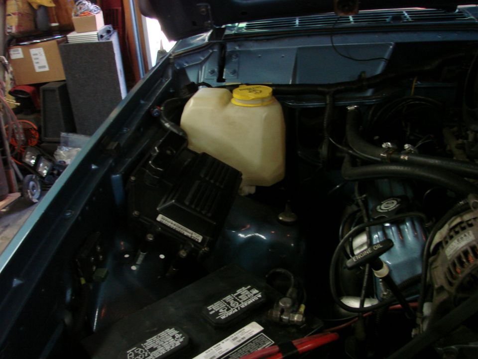 1991 Jeep Comanche engine bay showing coolant reservoir, battery, and engine components
