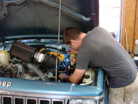 1991 Jeep Comanche - Mechanic performs maintenance on a 1991 Jeep Comanche engine, focusing on the engine bay components.