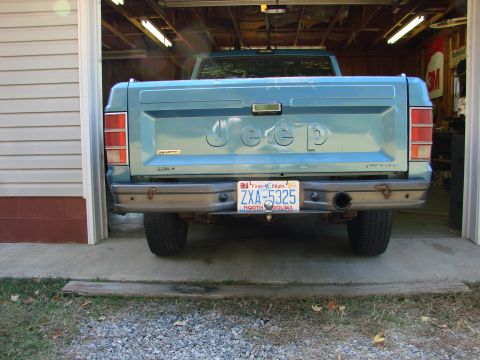 1991 Jeep Comanche - Rear view of a teal Jeep pickup truck, partially inside a garage, displaying a North Carolina license plate.