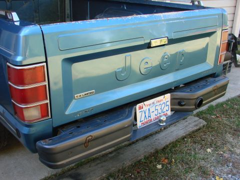 1991 Jeep Comanche - Rear view of a blue 1991 Jeep Comanche pickup truck, showing the tailgate with embossed 'Jeep' lettering and a '4.0 LIMITED' badge.