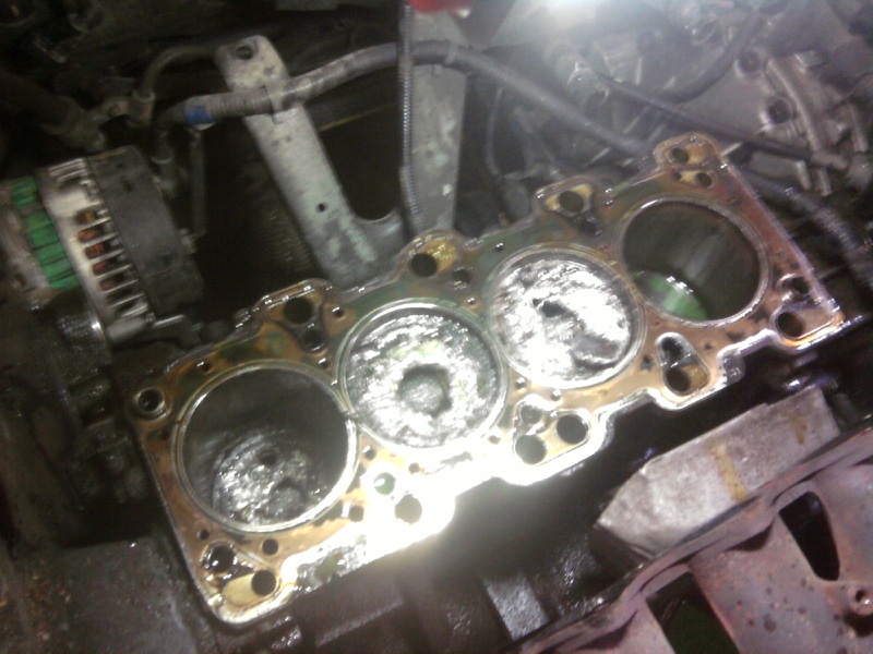 Engine block with damaged head gasket and pistons visible