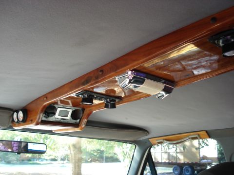 1992 Ford C-350 (Centurion Conversions) - Highly customized vehicle headliner with a wide burl wood console holding chrome-trimmed speakers, gauges, and accessories.