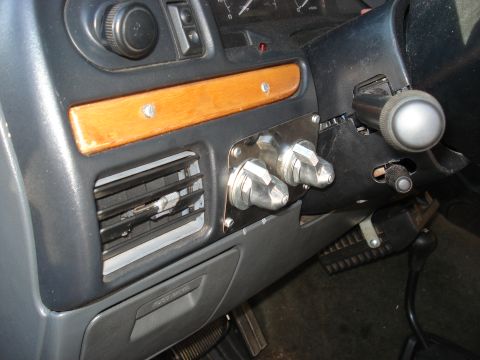 1992 Ford C-350 (Centurion Conversions) - Interior dash view of a Ford truck showing a gray dashboard with a wood trim panel, chrome dash vent, and a metal plate mounting two large…