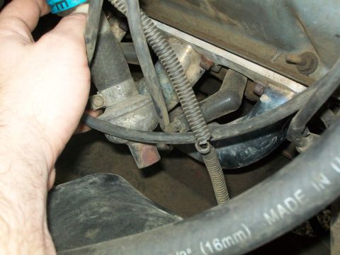 1987 Ford Bronco - Close-up of engine bay components, with a hand adjusting a hose clamp. Text on a hose reads 'MADE IN U.S.A.'