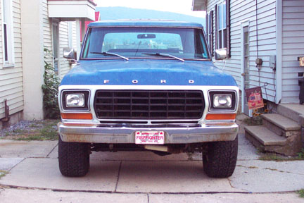 1979 Ford Bronco - This blue Ford pickup truck is parked in front of a house, with a 'Firefighter' license plate visible.