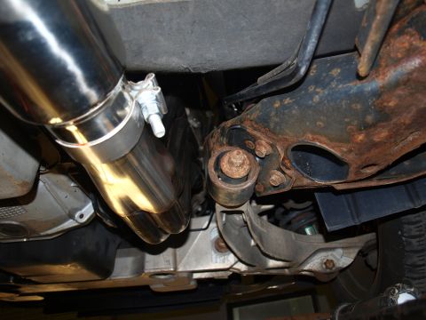 1998 Ford Crown Victoria - Underbody shot looking up at a polished stainless steel dual-tip exhaust muffler outlet clamped alongside the transmission pan and drivesha…
