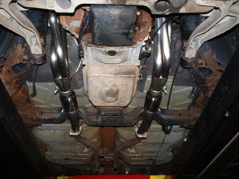 1998 Ford Crown Victoria - Underbody view on a lift showing a new pair of polished stainless dual exhaust pipes with flanged slip joints running back on either side o…