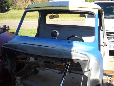 1954 Ford F-100 - The cab of a vintage Ford truck is shown, awaiting restoration with its windshield removed and parts of the bodywork exposed.