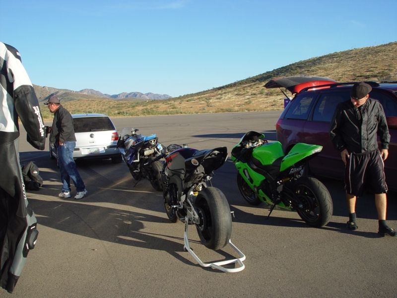 Green sportbike parked on asphalt with other motorcycles and a car