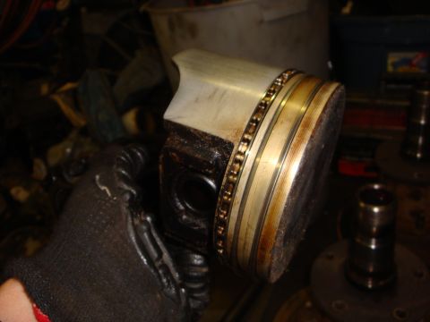 1989 Ford Bronco - A piston with its rings is held by a gloved hand, likely during engine maintenance.