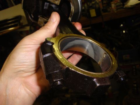 1989 Ford Bronco - A connecting rod with its bearing is held up for inspection, likely as part of engine maintenance.