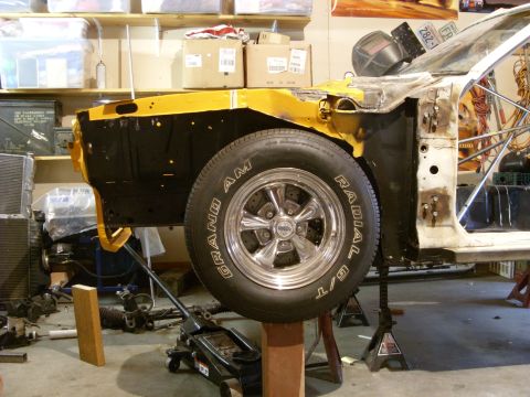 1978 Ford Mustang II - 1978 Ford Mustang II front section in repair, showing fender and wheel assembly.