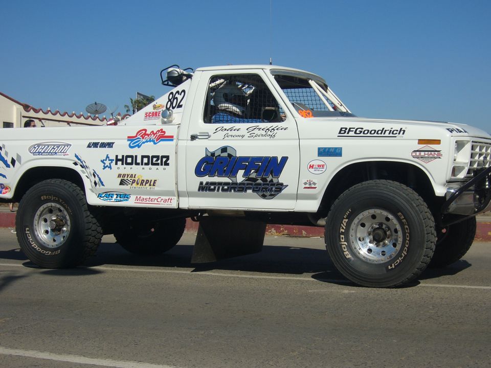 White off-road truck with racing decals, side view