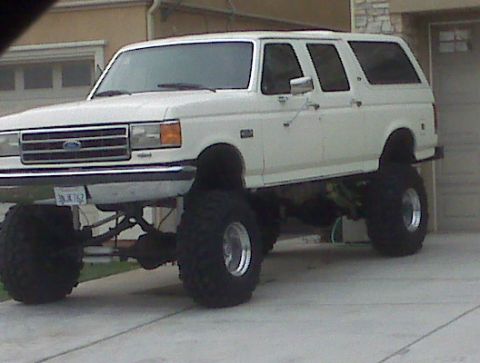 1986 Ford Bronco - This lifted SUV features oversized tires and a prominent front grille, suggesting a model year around 1987.