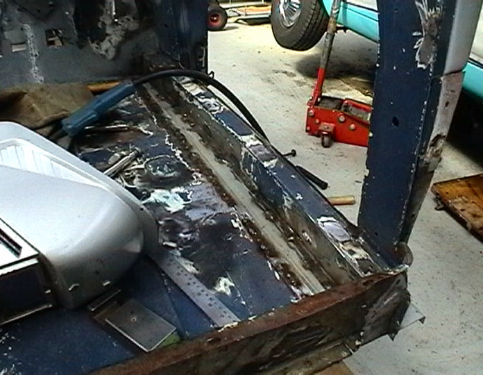 Interior of a car undergoing restoration with tools and a jack visible