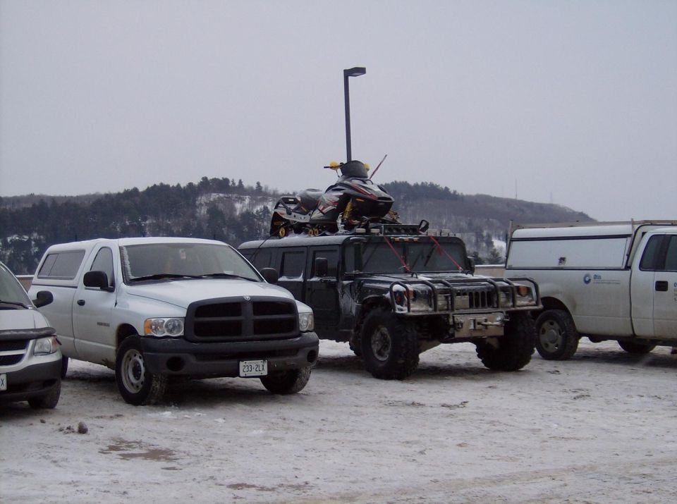 Humvee with snowmobile on roof, parked in snow