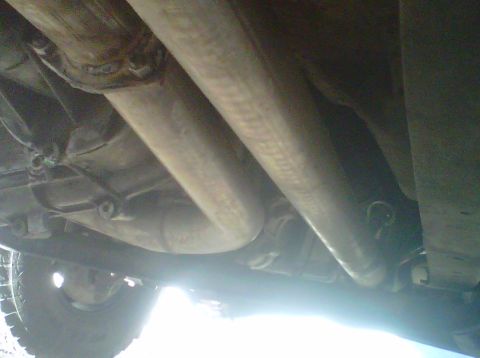 1994 Ford F-150 - The underside of a vehicle, showing the exhaust system and a portion of the tire.