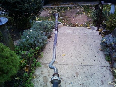 1990 Ford Bronco - A long aluminized exhaust intermediate pipe with several bends and a flared flange end laid out lengthwise on a concrete walkway to check i…