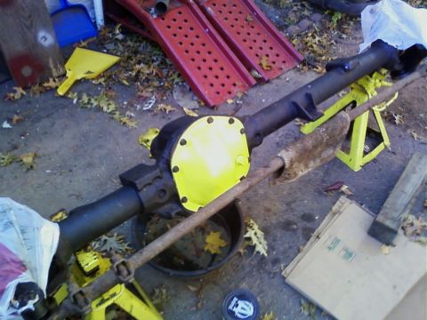 1990 Ford Bronco - Rear axle assembly with a bright yellow differential cover is supported by jack stands.