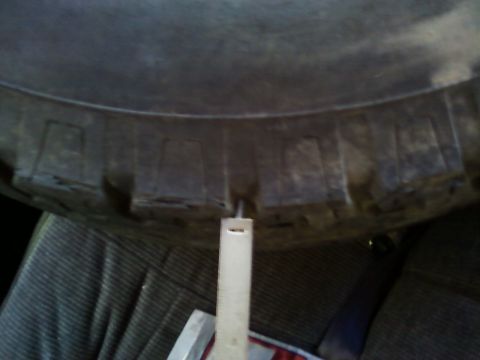 1990 Ford Bronco - A ruler is used to measure the tread depth of a tire inside a vehicle.
