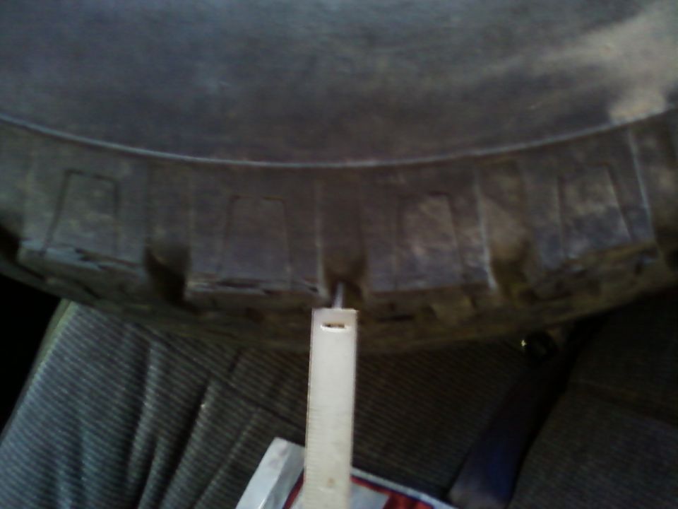 Measuring tire tread depth with a ruler inside a vehicle