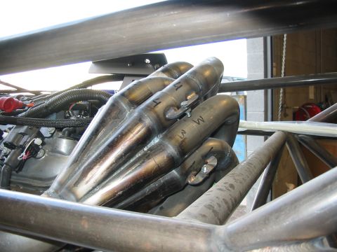1993 Ford Taurus - Close-up view of a custom exhaust manifold with visible markings, connected to engine components.