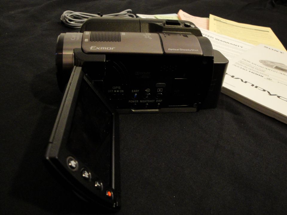 Sony Handycam camcorder with LCD screen open, "Exmor" and "Optical SteadyShot" visible