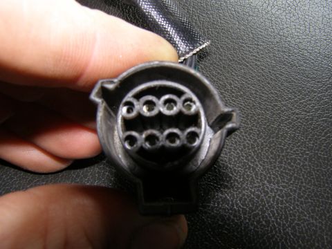 1993 Ford Bronco - A hand holds a 7-pin trailer wiring connector, showing the arrangement of the pins.