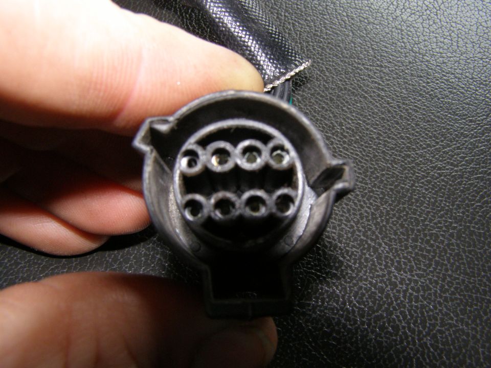 Close-up of a 7-pin trailer wiring connector with a hand holding it