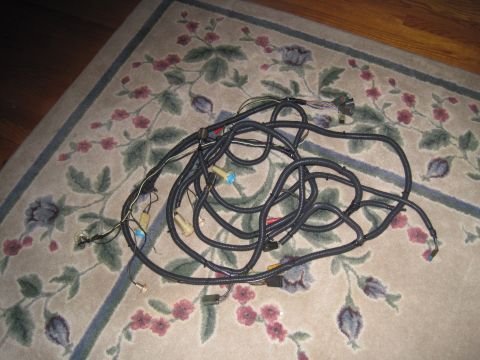 1979 Ford Bronco - A tangled wiring harness lies on a floral rug, various connectors and black protective tubing.