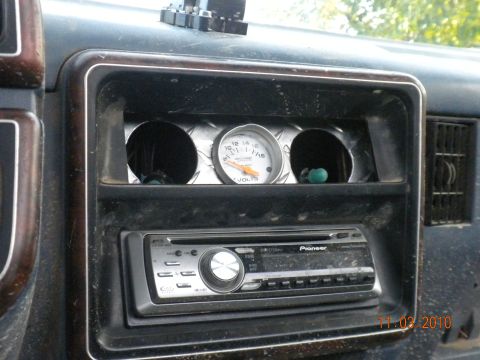 1989 Ford Bronco - The interior of a vehicle shows a voltage meter and an aftermarket stereo system.