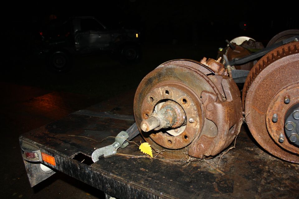 rusty brake parts on a trailer, with a dark pickup truck in the background
