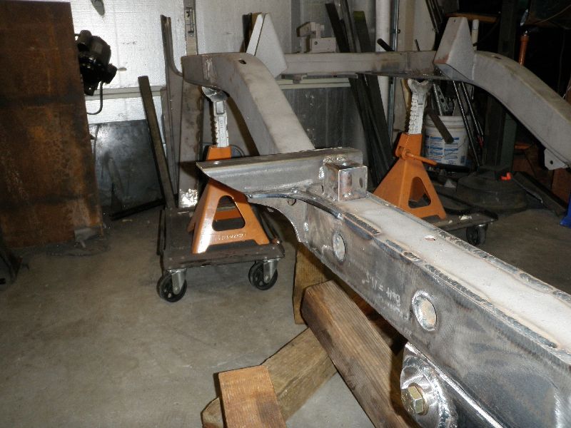 Vehicle frame on jack stands with visible welding and bolt details