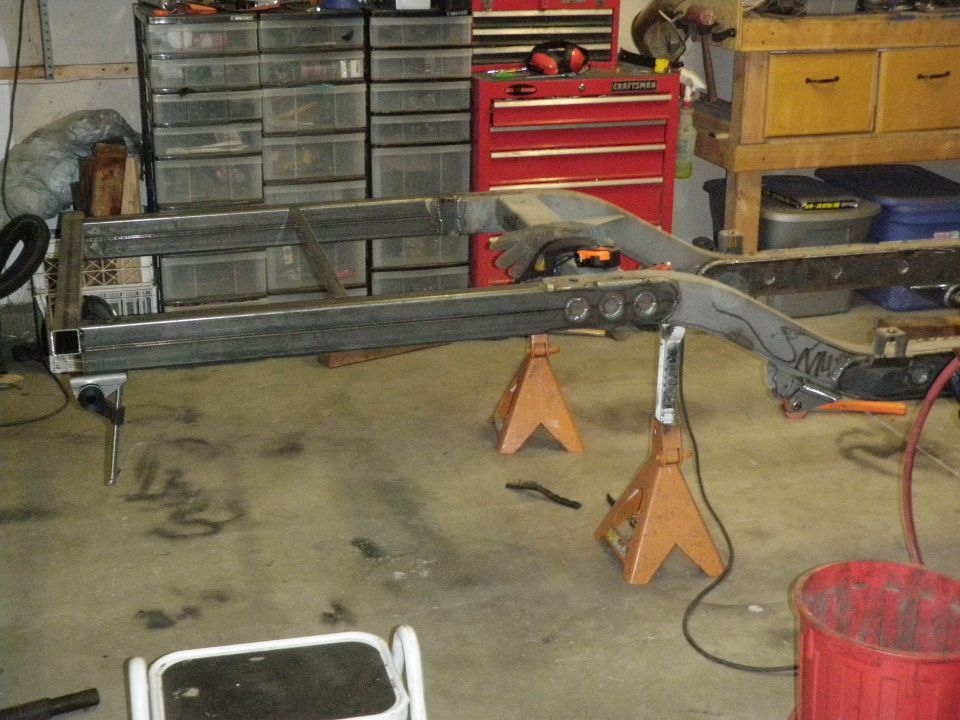 Vehicle frame on jack stands with metal fabrication visible