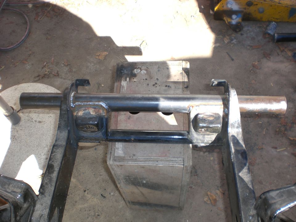 Black welded frame section with cross tube and bare metal ends resting on a metal box outdoors
