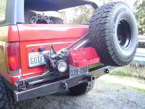 1989 Ford Bronco - Rear view of a red 1989 Ford Bronco, a spare tire, Hi-Lift jack, and a custom metal bumper.
