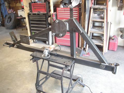 1989 Ford Bronco - Custom fabricated rear bumper assembly with a spare tire mount, shown with a grinder on a stand.