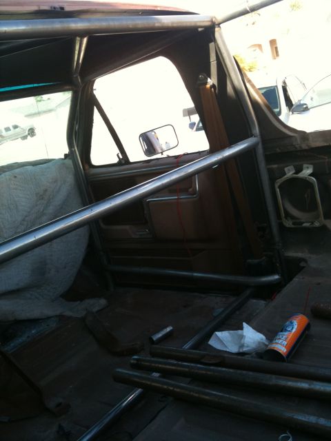 1982 Ford Bronco - The interior of a vehicle is visible, showing a roll cage and worn seats.