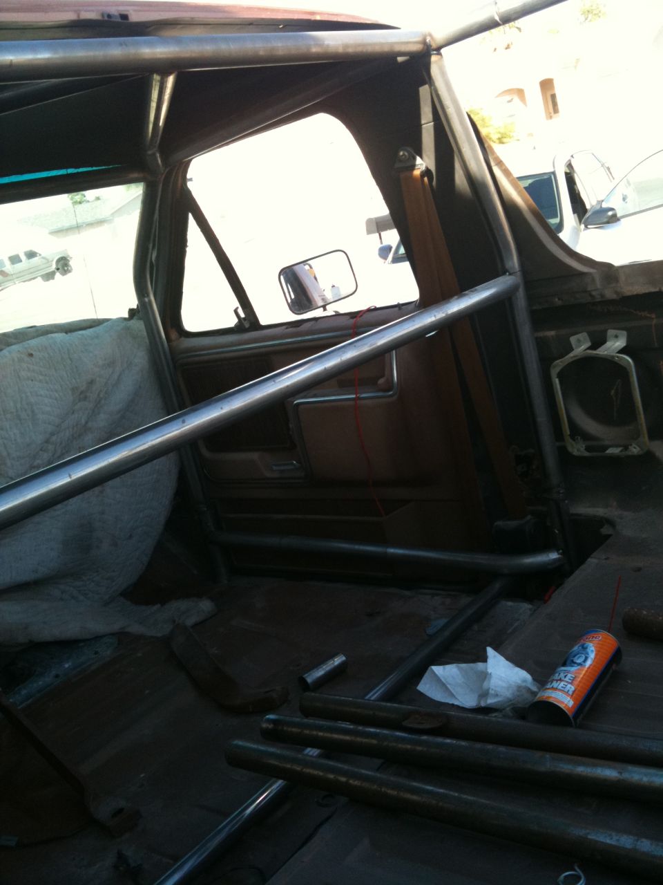 Interior of a vehicle with a roll cage, worn seats, and metal bars on the floor