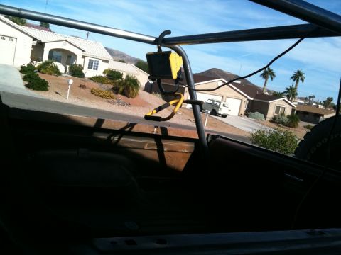 1982 Ford Bronco - View from inside a vehicle's roll cage, looking out at a white SUV parked on a residential street.