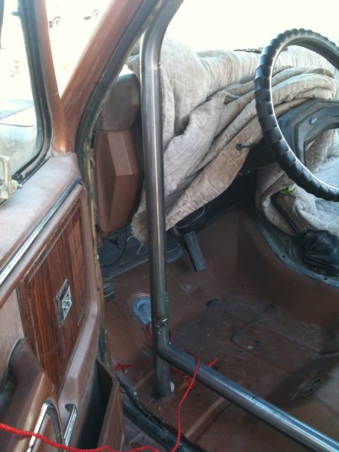 1982 Ford Bronco - Roll cage installation in a vehicle interior, with a blanket covering the passenger area.
